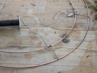 Wire being affixed to wire Christmas wreath ring
