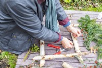 Woman tying the four birch sticks together