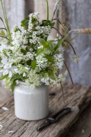 Simple posy of white and green in an old ceramic pot. Rustic setting.