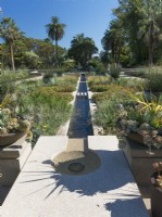 Rill bisecting lushly planted beds at Huntington Botanical Gardens. Containers filled with succulents on pedestals