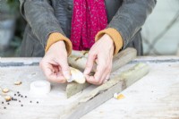 Woman placing masking tape across the middle of the sawn face of the birch sticks