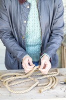 Woman tying string to mark the centre of both lengths of rope