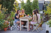 Women sat enjoying cake and drinks on roof terrace.