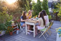 Women sat enjoying cake and drinks on roof terrace.