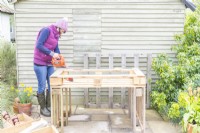 Woman cutting off excess lengths of wood from the pallet