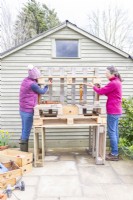 Woman holding up shelf while the other marks bracket position