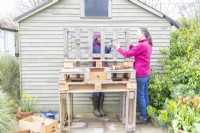 Woman screwing blocks to the back of the bench to use as brackets for the shelf