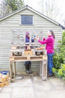 Woman screwing blocks to the back of the bench to use as brackets for the shelf