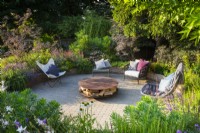 Sunken seating area with freestanding lounge chairs and corten fire pit with wood storage. 