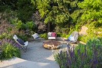 Sunken seating area with freestanding lounge chairs and fire pit with wood storage. 