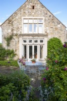 Rustic wire table and chairs on a patio with terracotta pot planted with Verbena.  The Old Rectory, Isle of Wight