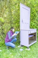 Woman using brackets to secure the door to the back of the cabinet