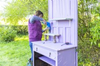 Woman securing shelf to the wooden bracket