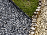 Edging detail of thick stemmed bamboo tubes separating two colours of gravel pathway and lawn. Floriade Expo 2022 International Horticultural Exhibition Almere Netherlands