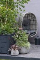 Grey pots planted with Pelargonium 'Grey Lady Plymouth' above Holcus mollis 'Albovariegatus', and Heuchera 'Pinky Panky'. Designer: Nikki Hollier.