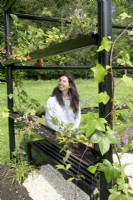 Strawberries and Geranium growing in recycled black downsprout. Designer looking at strawberry in city garden of 6 m2.