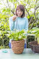 Woman holding up chain on hanging basket