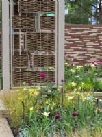 The Stitchers' Garden featuring soft yellows and deep pinks with tapestry walls and willow screens.