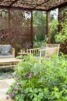 Sitting arrangement in pavilion  of metal screens with  Morris's Willow Boughs pattern, surrounded by herbaceous beds with Astrantia -  Morris and Co.