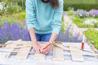 Woman marking a guiding line for attaching the burlap to the planks