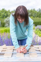 Woman marking a guiding line for attaching the burlap to the planks