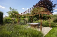 An artisinal wrought iron pergola designed and made for an outdoor living space by artist blacksmith Paul Elliot in a private garden.