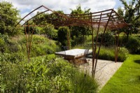 An artisinal wrought iron pergola designed and made for an outdoor living space by artist blacksmith Paul Elliot in a private garden.
