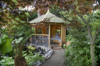 Summerhouse positioned on path next to the pond at Hamilton House garden in May 