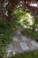 Rustic paving slabs and gravel lead a path from a wide end to a narrow end in a  triangular formation.Spring