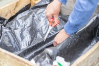 Woman cutting drainage holes in the liner