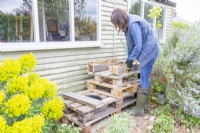Woman placing pieces of the pallets at the front and back of the raised platform