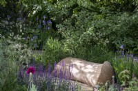 Beautifully moulded Oak bench in small garden in dappled shade