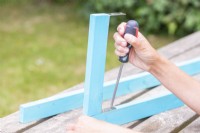 Woman screwing pieces of wood together with brackets