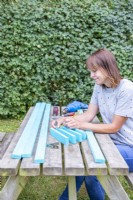 Woman marking where to place the brackets on the pieces of wood