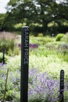 Black wooden posts with the names of renowned women gardeners used to identify growing areas at a flower farm in July