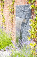 Waterfall feature on layered slate backing surrounded by plants