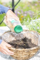 Woman pouring granular plant feed in basket