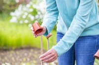 Woman placing small pots at the end of the bamboo canes