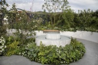 Circular water feature surrounded by green and white planting and circular paving in CRUK Legacy Garden at Malvern Spring Gardening Festival 2022
