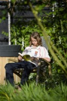 Teenager sitting reading in the garden.