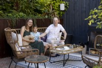 Family sitting on chair with dog in shady patio area in suburban garden