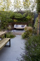 Garden patio with chairs and seating with borders in suburban garden