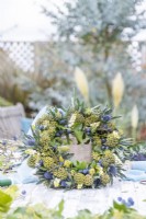 Ivy, Symphoricarpos and Eryngium wreath on wooden table