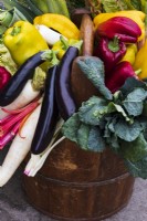 Colourful assortment of vegetables in wooden trug. Including aubergine, peppers, and mooli radishes.