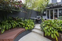 Curved composite timber bench seat in an innercity courtyard garden with steps leading to an upper level.