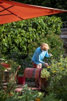Garden owner tidying flower bed in her London cottage garden, summer