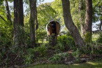 Gypsy caravan hidden behind shady garden border filled with Ferns beneath trees