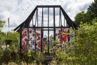 Representation of a Ukranian burnt cottage draped with rushnyk, an embroidered cloth.  What Does Not Burn - RHS Hampton Court Palance Garden Festival 2022