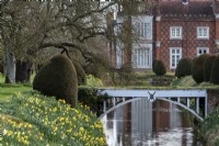 A bridge over the moat that surrounds the walled garden at Helmingham Hall.  In spring the clipped Yew, Taxus baccata cones  are surrounded by Daffodils.