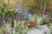 Water bowl feature in low maintenance gravel garden with drought-tolerant herbaceous plants to attract pollinators, such as Salvia, Eryngium, Eryngium, Stachys byzantina and Achillea 'Credo' - Turfed Out Garden, RHS Hampton Court Palace Garden Festival 2022